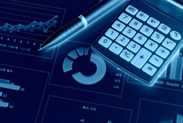 Calculator and pen sitting ontop of graphs and reports